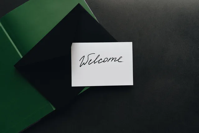 A minimalist flat lay of a black envelope with a 'Welcome' card on a dark background. What good email automation examples actually have in common