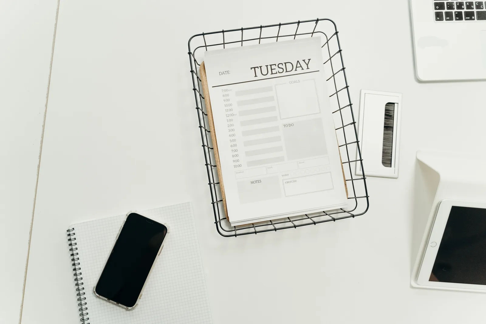 Top view of a neat office desk with a Tuesday planner, smartphone, and gadgets, perfect for scheduling and organization. Email campaign planning trends: signals to monitor