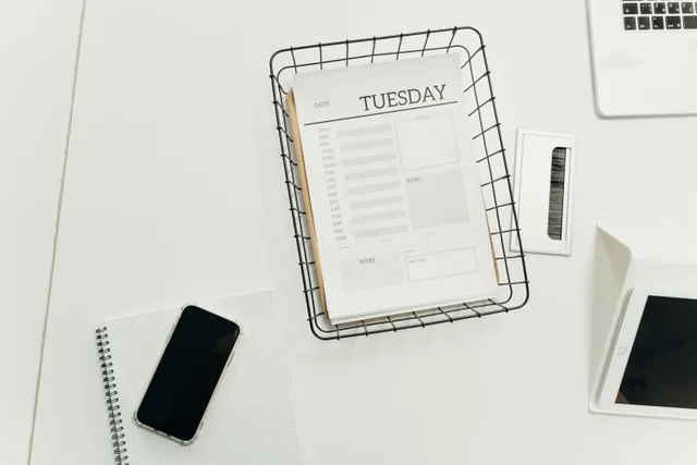 Top view of a neat office desk with a Tuesday planner, smartphone, and gadgets, perfect for scheduling and organization. Email campaign planning trends: signals to monitor