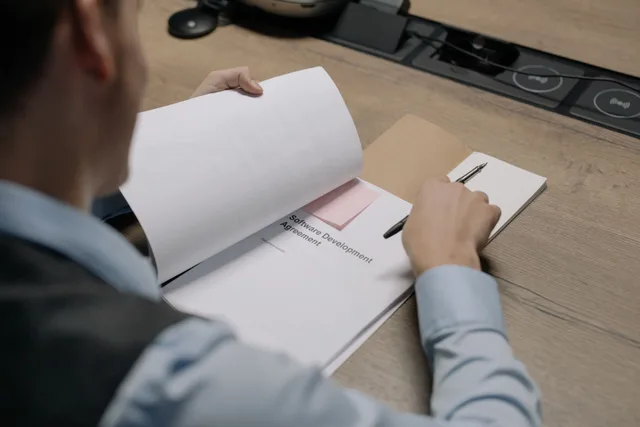 Business professional at the desk examining a software development agreement document. How to build a dated requirements set for Brevo, Kit, Mailchimp and MailerLite