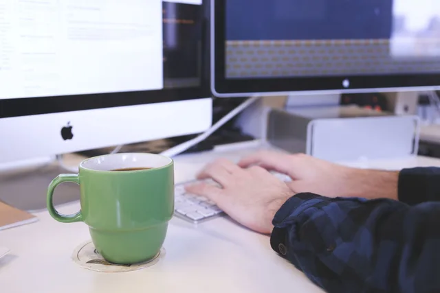 Person typing at a desk with coffee and computer screens. Perfect for business or technology themes. Email marketing software use cases and the controls each one needs