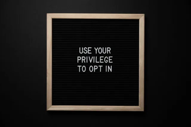 From above composition of contrast blackboard in wooden frame with white USE YOUR PRIVILEGE TO OPT IN title on black background. 9 details of email marketing strategy tools people miss