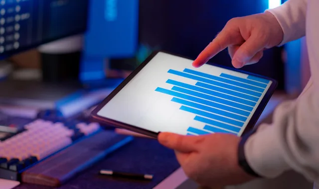 Business professional analyzing bar chart on tablet in office setting, highlighting data insights. Email segmentation tools: how to evaluate them