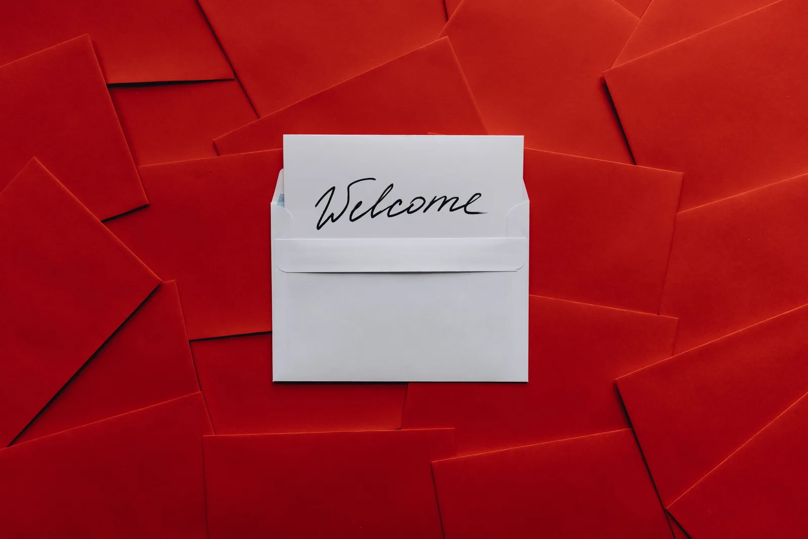 A white card with 'Welcome' text in an envelope against a red envelope background. Email subscriber journey stages explained with examples