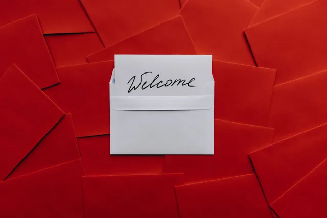 A white card with 'Welcome' text in an envelope against a red envelope background. Email subscriber journey stages explained with examples