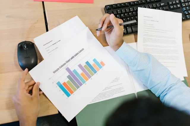 A business analyst reviews a colorful bar chart and documents at a desk, indicating data analysis. Choosing email marketing software without vendor names: an eight step method