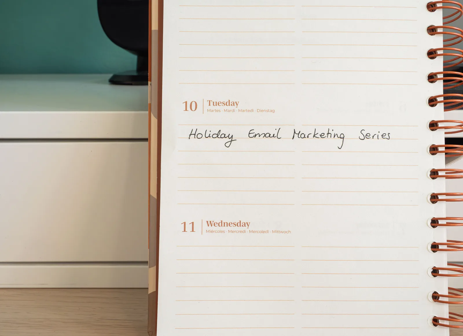 Planner open on a desk with handwritten 'Holiday Email Marketing Series' note. How to improve email list building: audit, tag, compare by source