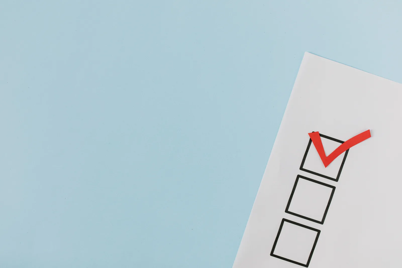 A checklist with a red checkmark symbolizing a completed task on a pastel blue background. Improving small business email marketing: what to repair before sending more